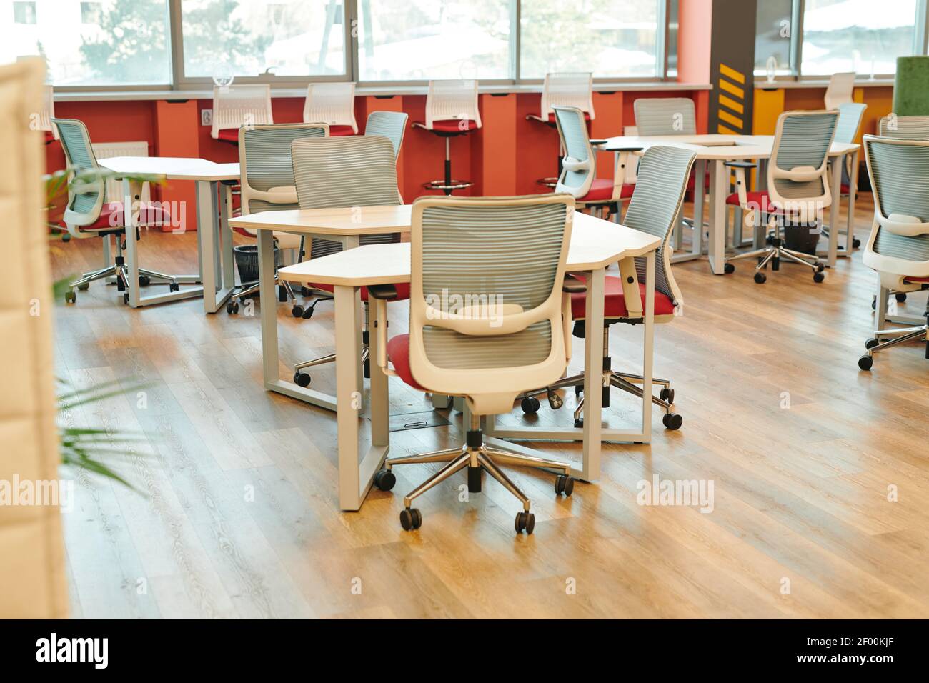 Interno di un grande ufficio open space contemporaneo con molte sedie da tavoli e lungo windowsills senza lavoratori o dirigenti intorno Foto Stock