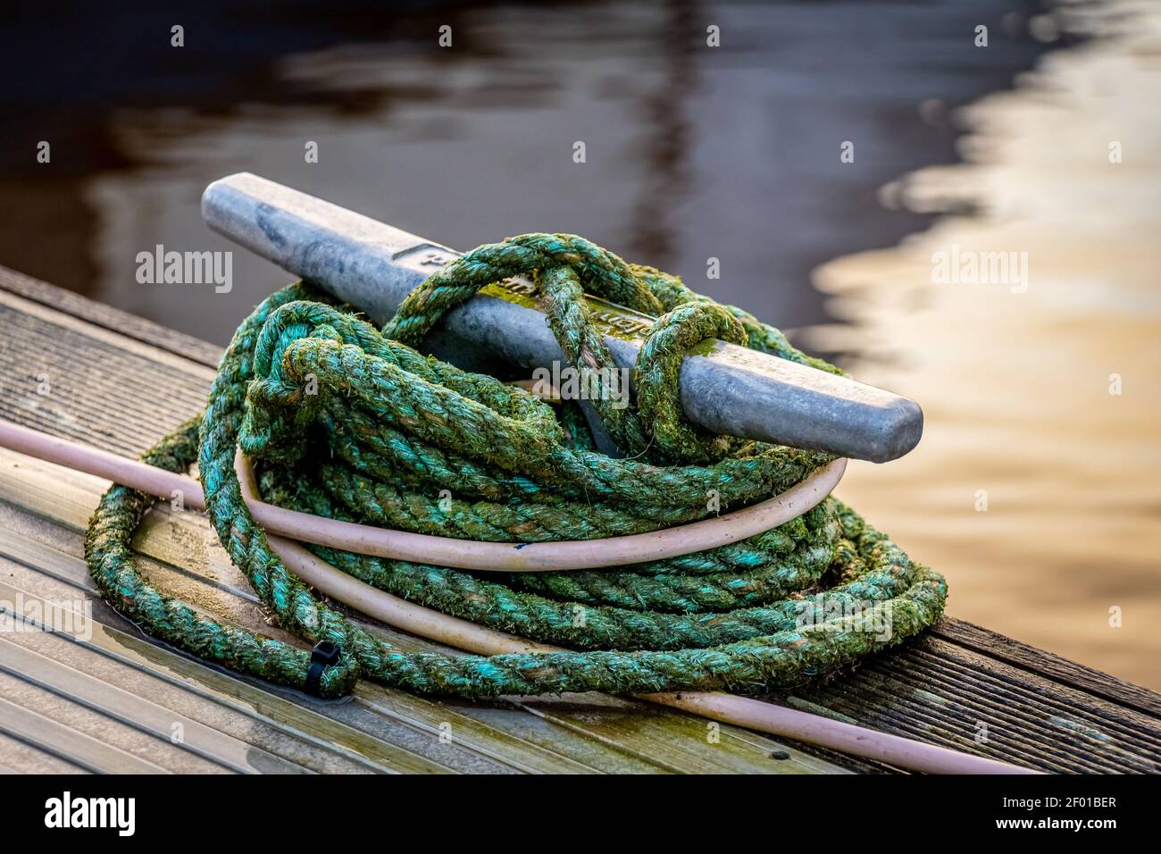 Corda legata intorno ad un bollard di metallo che ormeggi su un legno molo Foto Stock