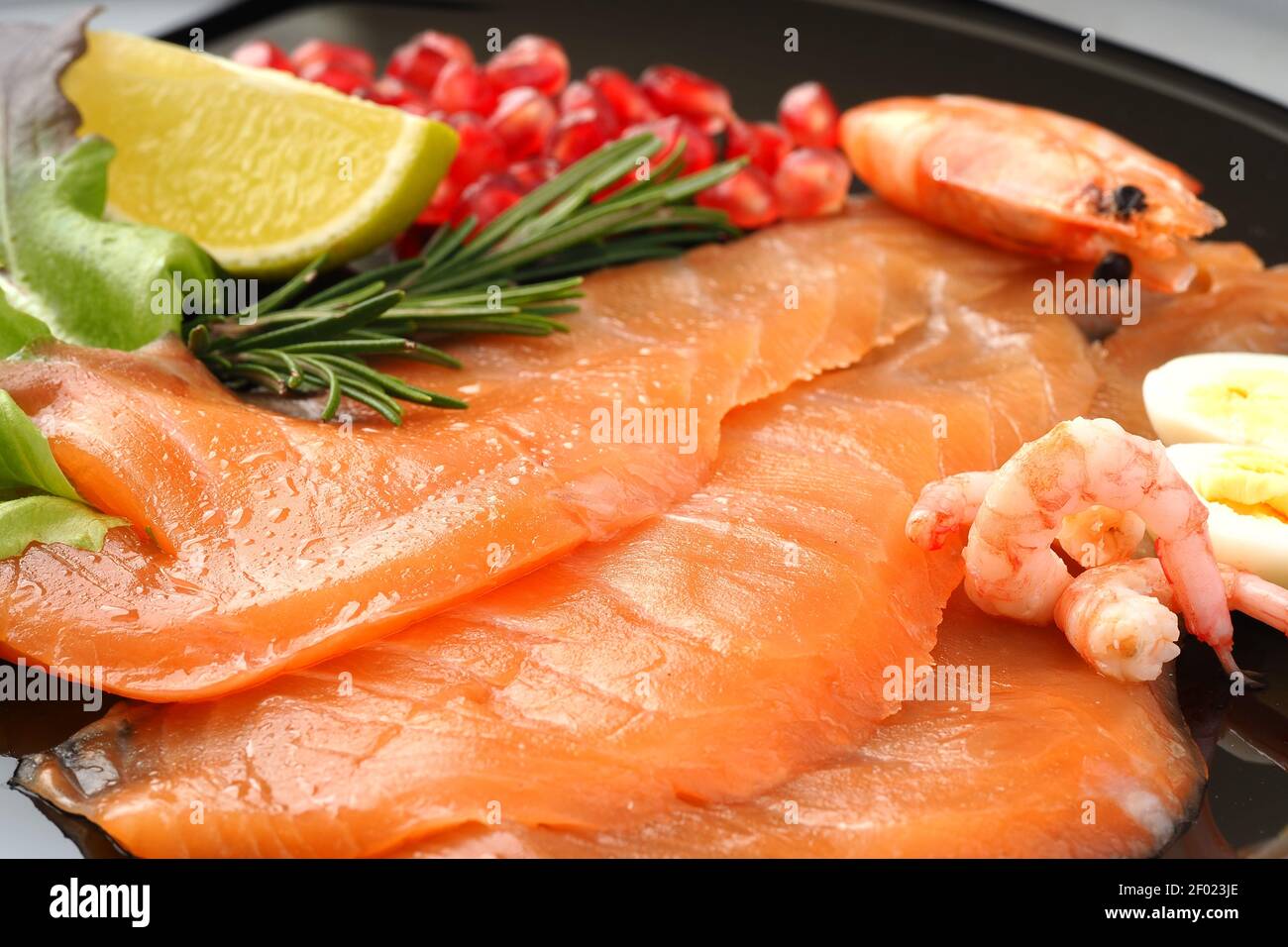 Pesce rosso. Piatto di pesce, gamberi salati di salmone su un piatto piatto con limone e rosmarino. Foto Stock