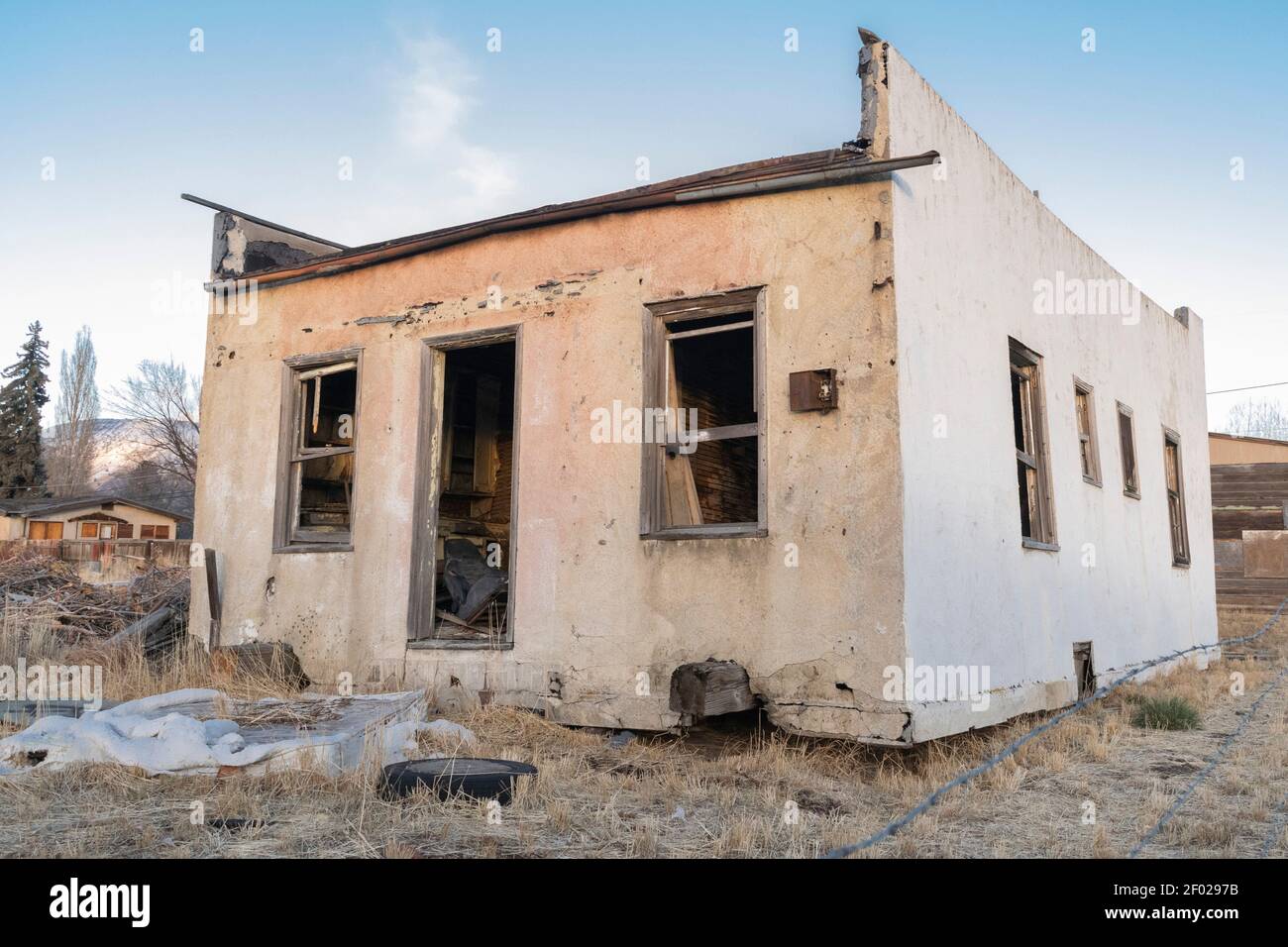Un edificio abbandonato in stucco si affaccia sul sole che tramonta a Klamath Falls, Oregon. Foto Stock