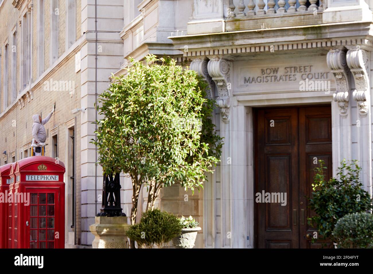 Londra, Regno Unito - 23 Feb 2021: Un lavoratore pulisce l'esterno dell'ex Bow Street Magistrates Court, che ha recentemente subito la conversione in un hotel e un museo di polizia, entrambi dovuti ad essere aperti nel 2021 una volta che le normative Covid lo consentono. Foto Stock