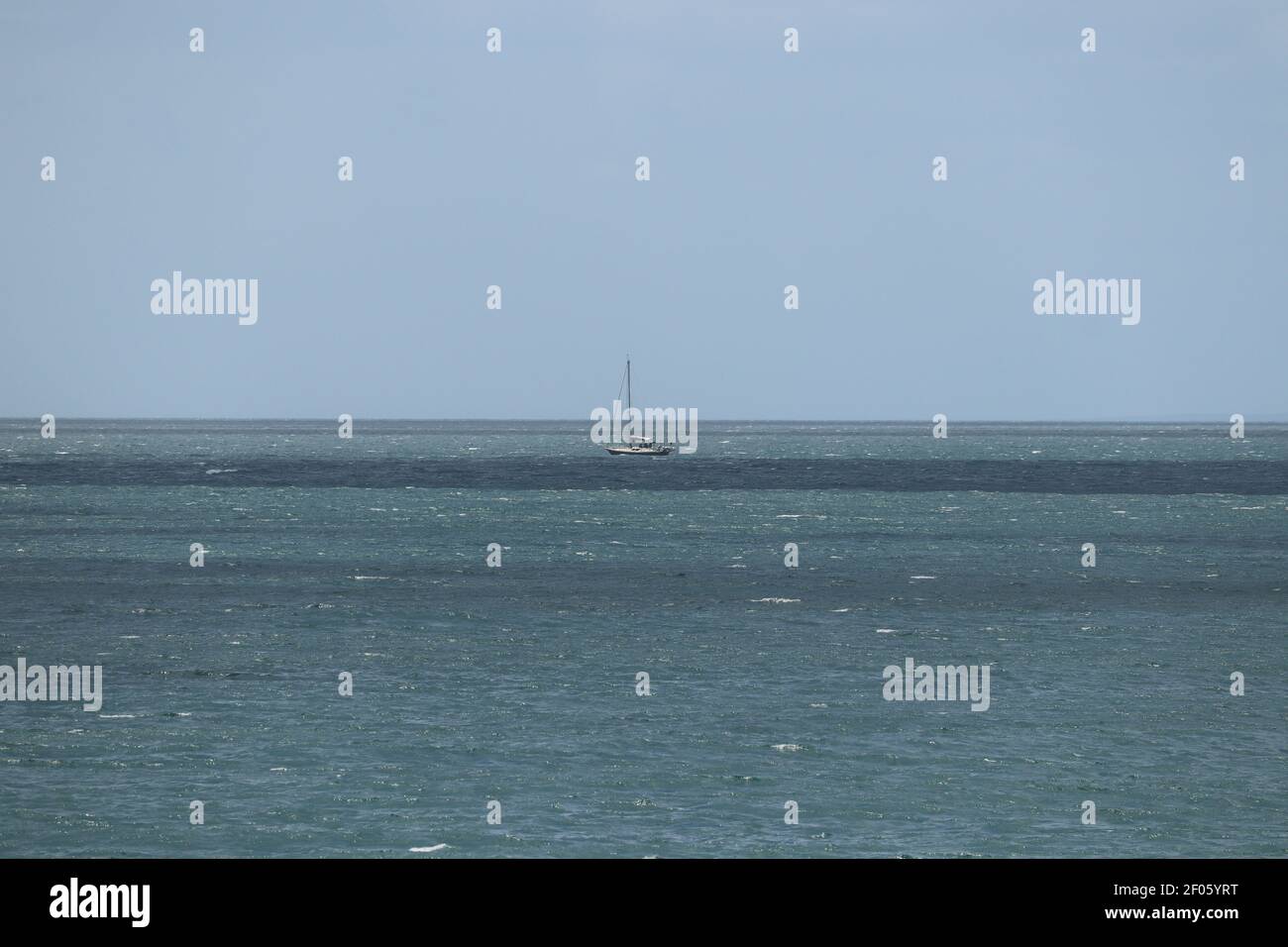 Barca a vela che cavalcano le onde agitate al largo della costa della cornovaglia Foto Stock
