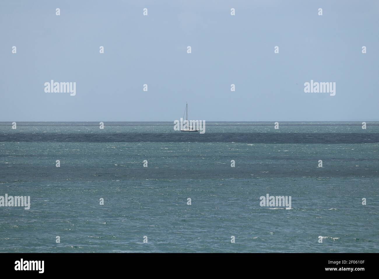 Barca a vela che cavalcano le onde agitate al largo della costa della cornovaglia Foto Stock