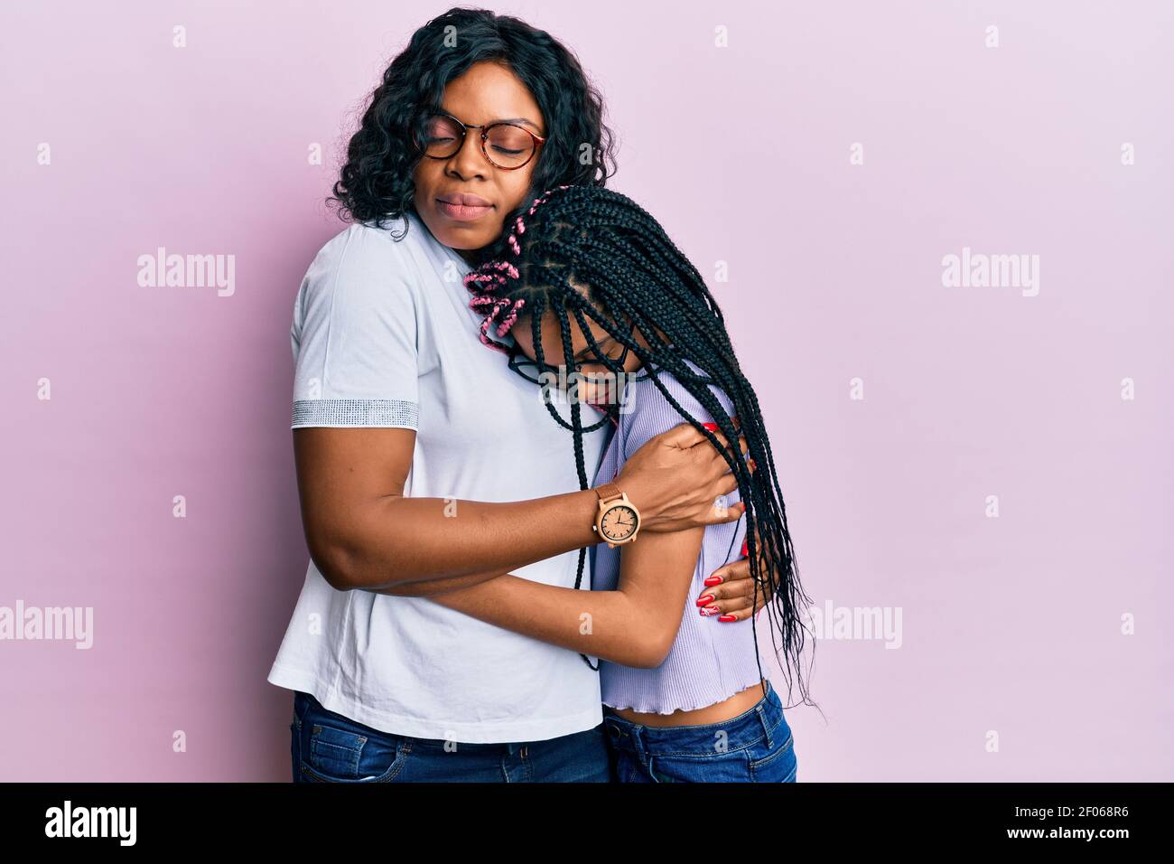 Bella madre afroamericana e figlia che indossa abiti casual e occhiali abbracciandosi felice e positivo, sorridente sicuro. Auto amore e. Foto Stock