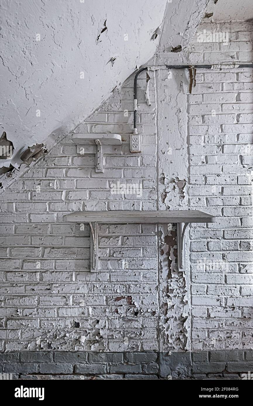 Peeling vernice bianca su muro di mattoni con mensola, interno di