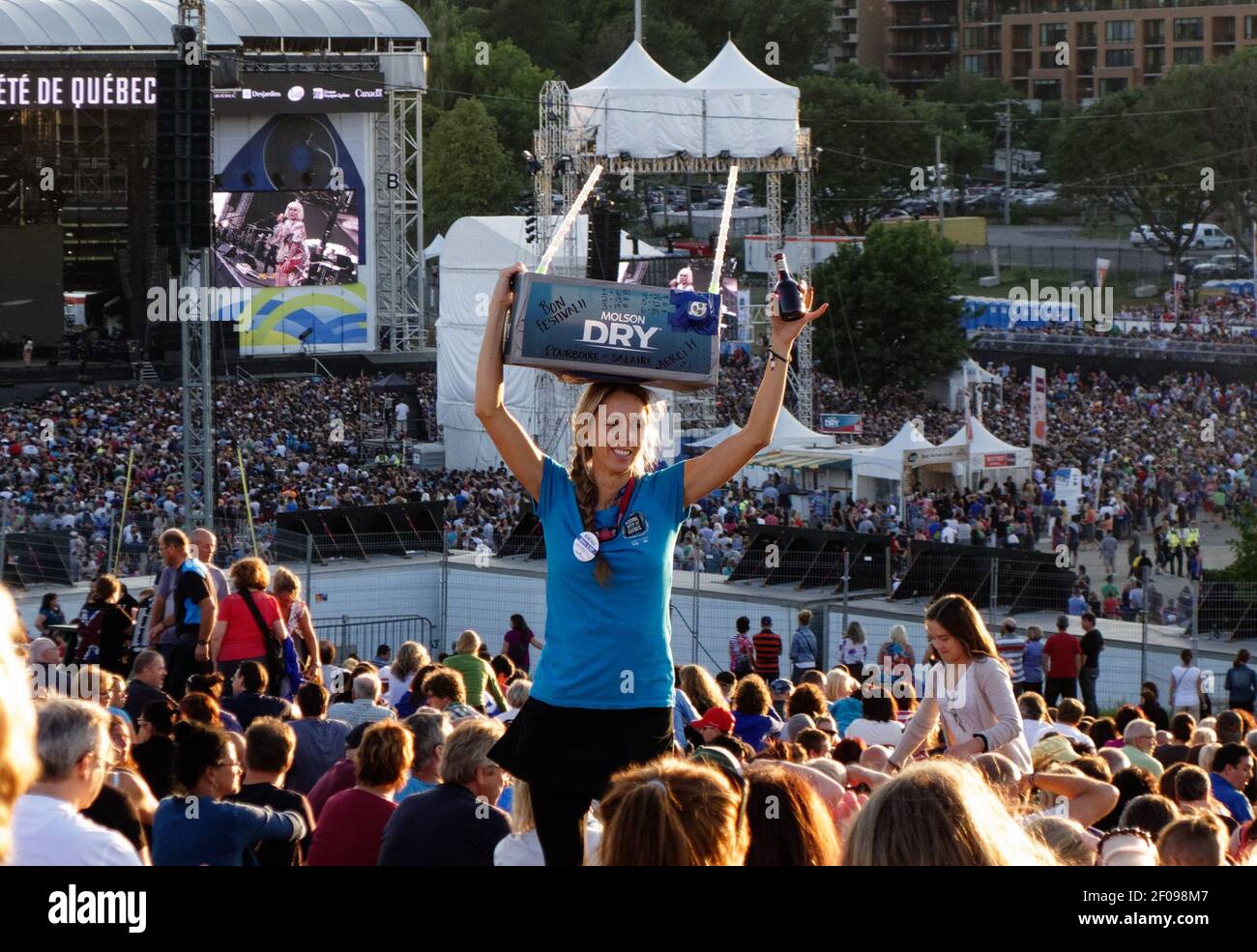 Una giovane donna che serve birra nella folla al Festival estivo di Quebec City (Festival D'été de Quebec) Foto Stock