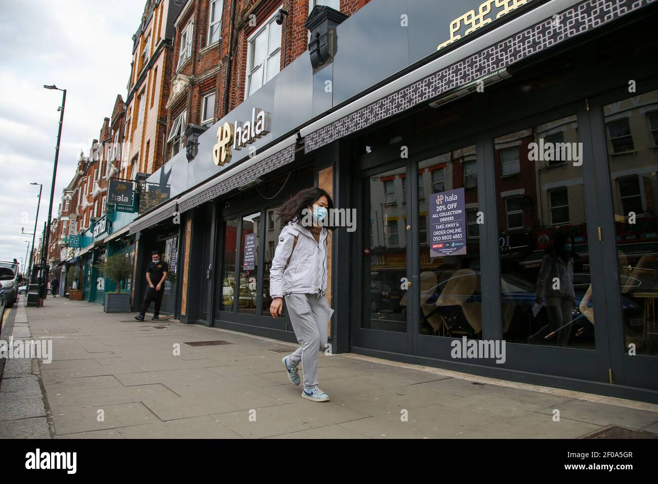 Londra, Regno Unito. 06 marzo 2021. Una donna che indossa una maschera facciale come precauzione contro la diffusione del covid-19 cammina oltre un ristorante a Londra durante il lockdown.il primo ministro Boris Johnson ha annunciato una roadmap per facilitare la restrizione di blocco con gli studenti della scuola primaria e secondaria per tornare a scuola l'8 marzo. Credit: SOPA Images Limited/Alamy Live News Foto Stock