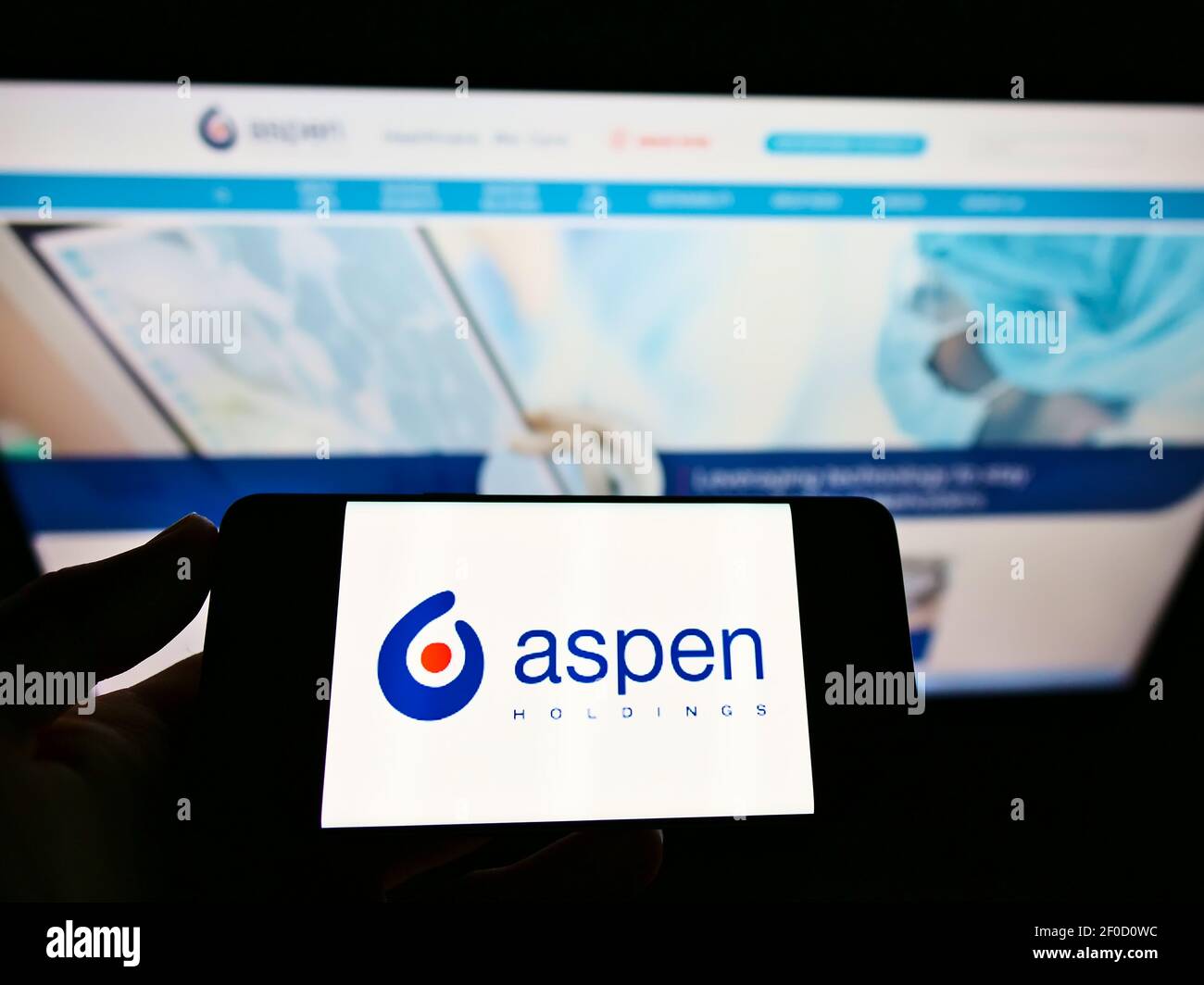 Persona che detiene il cellulare con il logo della società sudafricana Aspen Pharmacare Holdings Ltd sullo schermo davanti alla pagina web. Mettere a fuoco il display del telefono. Foto Stock