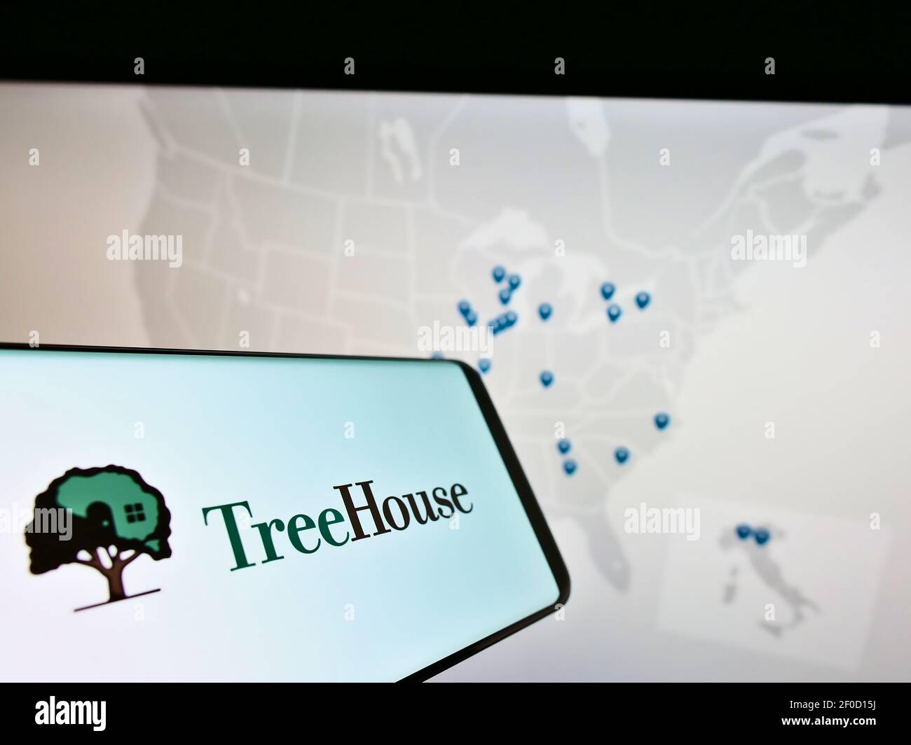 Telefono cellulare con logo della società americana di trasformazione alimentare TreeHouse Foods Inc. Su schermo di fronte alla pagina web con mappa. Mettere a fuoco il centro del display del telefono. Foto Stock