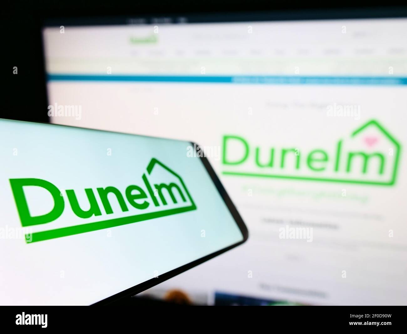Smartphone con logo del rivenditore britannico Dunelm (Soft Furnishings) Limited sullo schermo davanti al sito Web dell'azienda. Mettere a fuoco il centro del display del telefono. Foto Stock