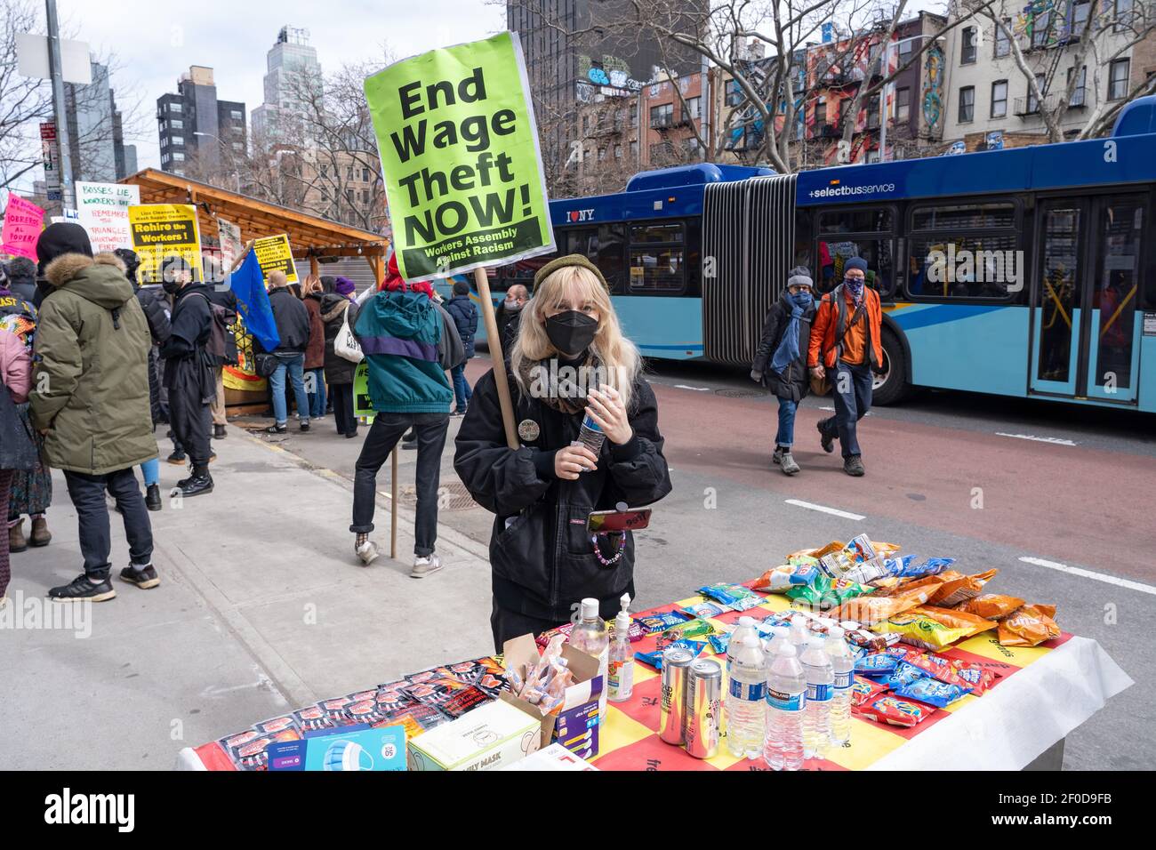 NEW YORK, NY – 6 MARZO: Il segno di tenuta del protestore ottiene lo spuntino libero e l'acqua dal Bodega del popolo durante una protesta dei Liox Cleaners il 6 marzo 2021 a New York City la catena dei Liox Cleaners sta affrontando una zattera di opposizione sulla scia del presunto 'sindacato busting'. Secondo la letteratura distribuita, 'il 19 febbraio, la catena del bucato Liox ha sparato le lavoratrici immigrate del Laundromat di alimentazione del lavaggio. Credit: Ron Adar/Alamy Live News Foto Stock