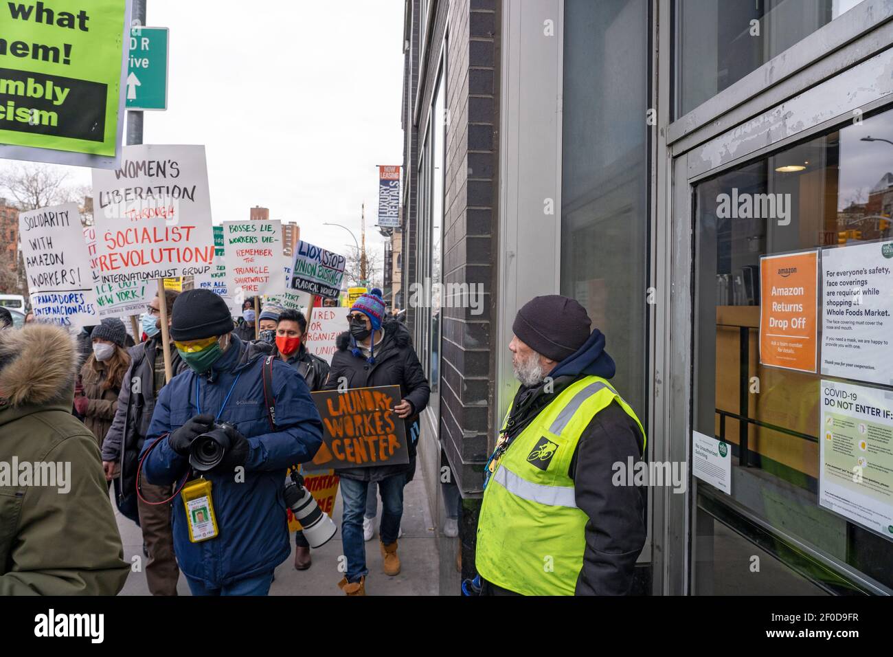 NEW YORK, NY – 6 MARZO: I dipendenti di Whole Foods Market guardano mentre i manifestanti del Centro dei lavoratori della lavanderia camminano da un Whole Foods Market su Huston a sostegno dell'Alabama Amazon Union durante una protesta di Liox Cleaners il 6 marzo, 2021 a New York la catena Liox Cleaners si trova di fronte a una serie di opposizioni sulla scia del presunto 'sindacal busting'. Secondo la letteratura distribuita, 'il 19 febbraio, la catena del bucato Liox ha sparato le lavoratrici immigrate del Laundromat di alimentazione del lavaggio. Credit: Ron Adar/Alamy Live News Foto Stock