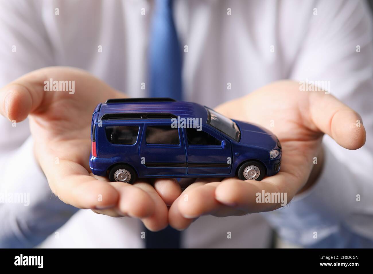 Uomo che tiene l'auto giocattolo blu nel suo closeup mani Foto Stock