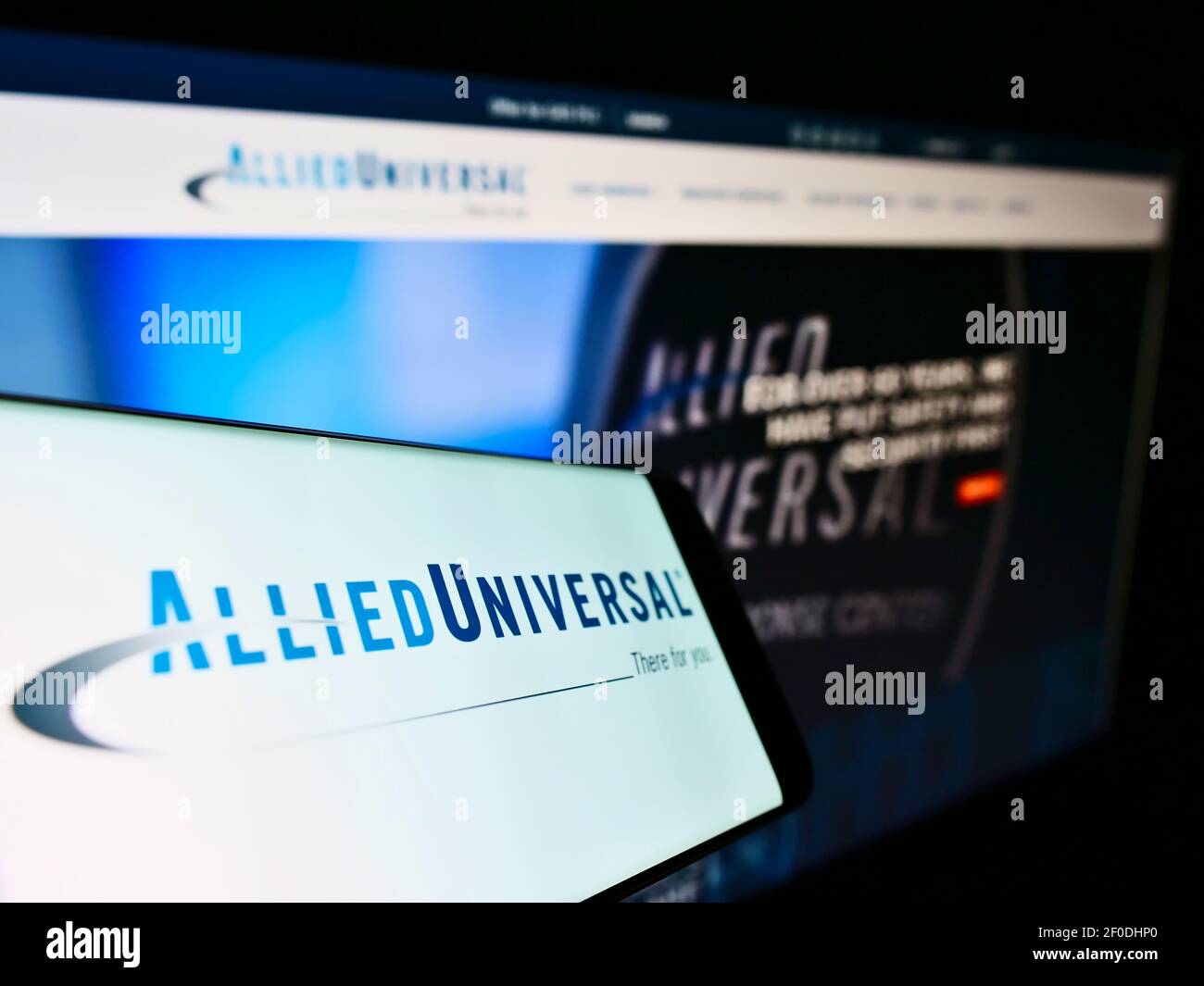 Telefono cellulare con logo della società americana Allied Universal Security Services LLC sullo schermo davanti alla pagina web. Mettere a fuoco il centro-destra del display del telefono. Foto Stock
