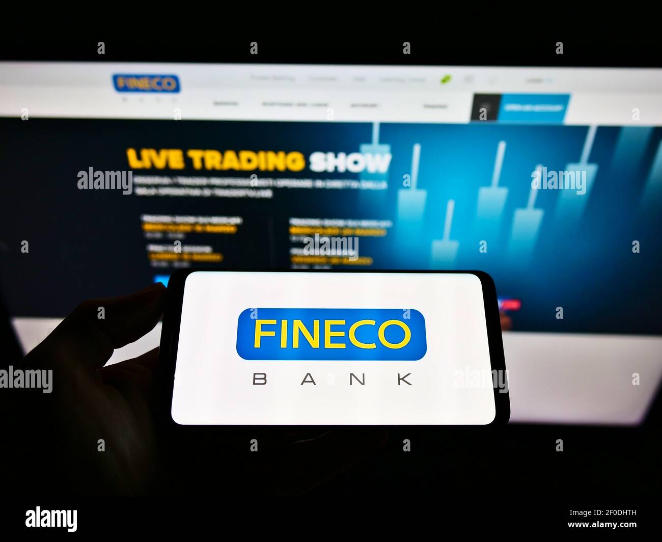 Persona titolare del cellulare con logo aziendale della banca italiana FinecoBank Spa. Sullo schermo davanti alla pagina web. Focus sul display del cellulare. Foto Stock