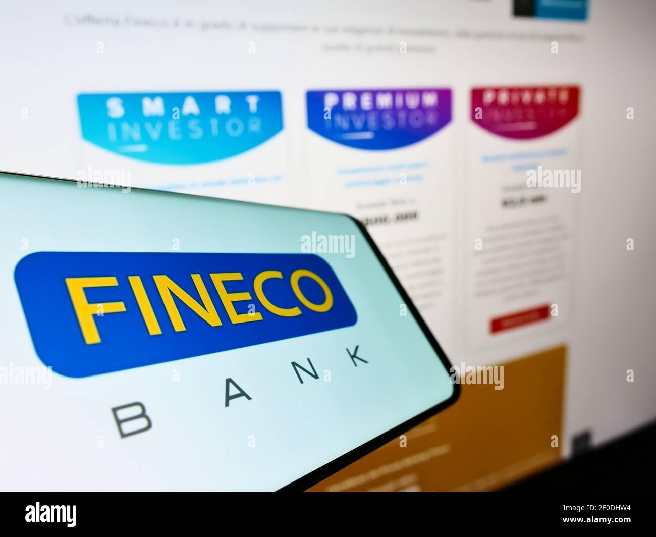 Telefono cellulare con logo commerciale della banca italiana FinecoBank S.p.A. sullo schermo davanti alla pagina web aziendale. Mettere a fuoco il centro-destra del display del telefono. Foto Stock