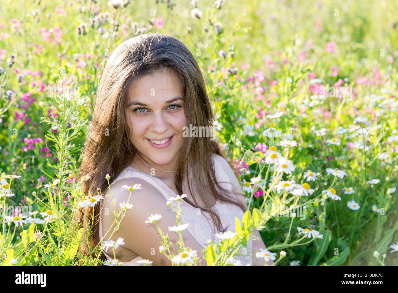 Bellissima con i capelli lunghi ragazza sulla radura con fiori di prato Foto Stock