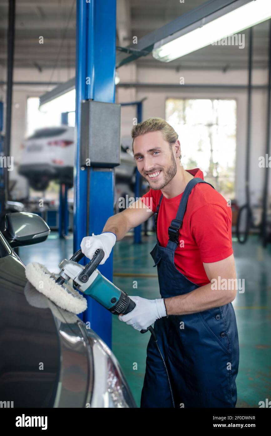 Uomo che lavora in garage di buon umore Foto Stock