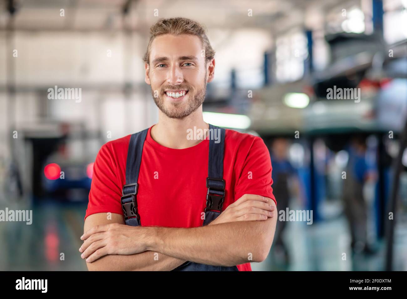 Uomo di riparazione felice in piedi con le braccia ripiegate sul petto Foto Stock