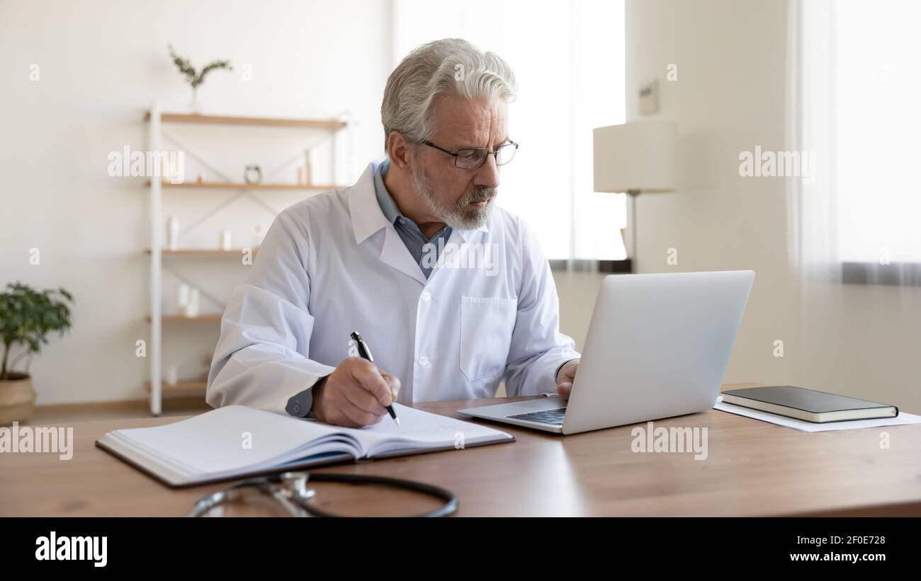 Medico maschile maturo lavoro sul computer in clinica Foto Stock