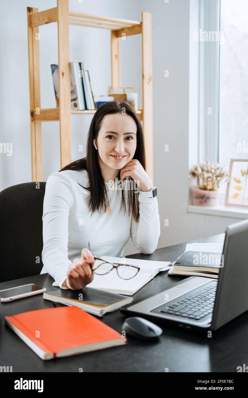 Piccole imprese, lavoro autonomo, microimprenditori, ragioniere, concetto di proprietà. Giovane donna d'affari che lavora con il laptop e documenti dall'ufficio Foto Stock