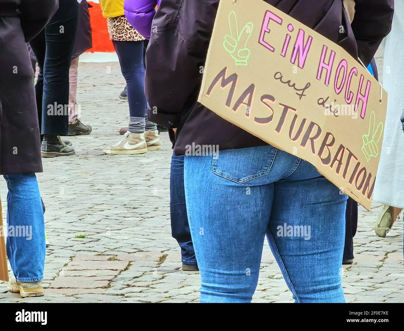 Poster con l'iscrizione Hurray per masturbazione, sul retro di un dimostratore con pantaloni jeans blu stretto al giorno della donna. Braunschweig, Germania, Foto Stock