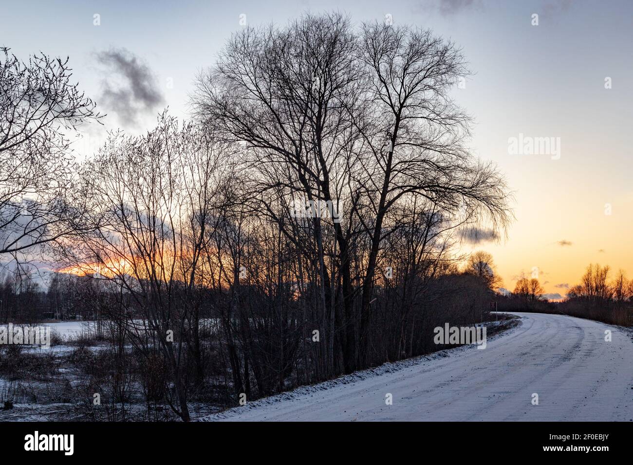 Bellissimo tramonto blu arancio su una strada innevata. Paesaggio invernale. Foto Stock