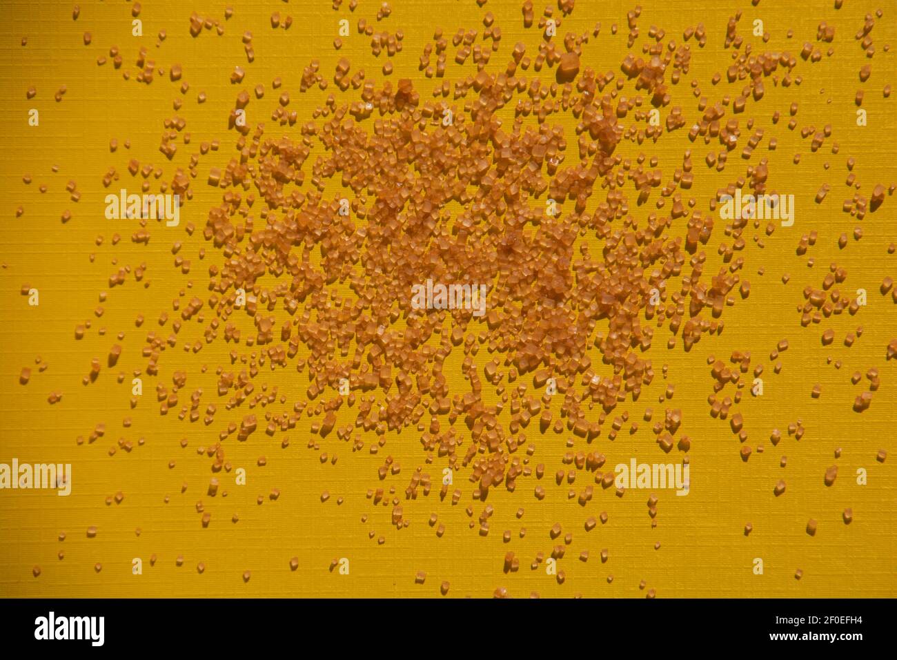 cubetti di cristallo di zucchero marrone dorato su sfondo di foglio di carta giallo Foto Stock