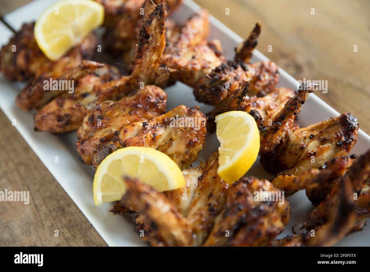 Ali di pollo britanniche che sono state spiedate e grigliate dopo la marinatura in un mix di spezie libanesi. Guarnito con limoni a fette. Inghilterra GB Foto Stock