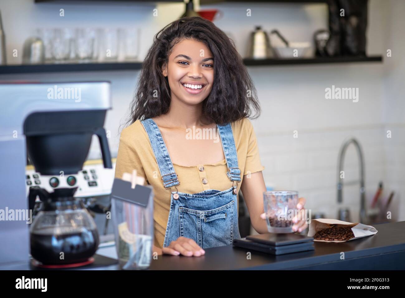 Donna felice con chicchi di caffè in vetro Foto Stock