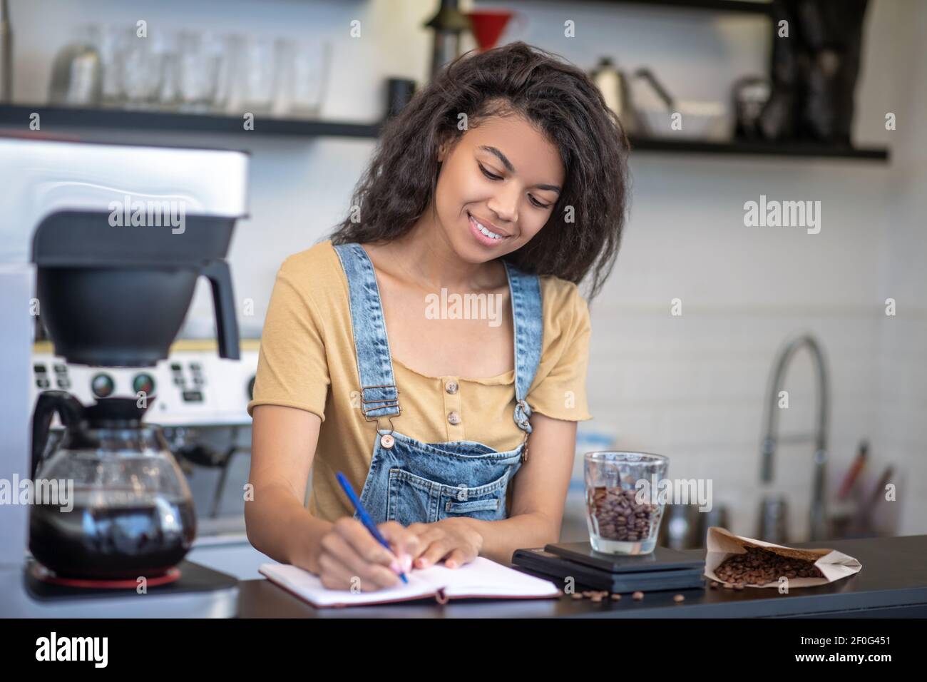 Bella donna che scrive nel notebook al bar Foto Stock