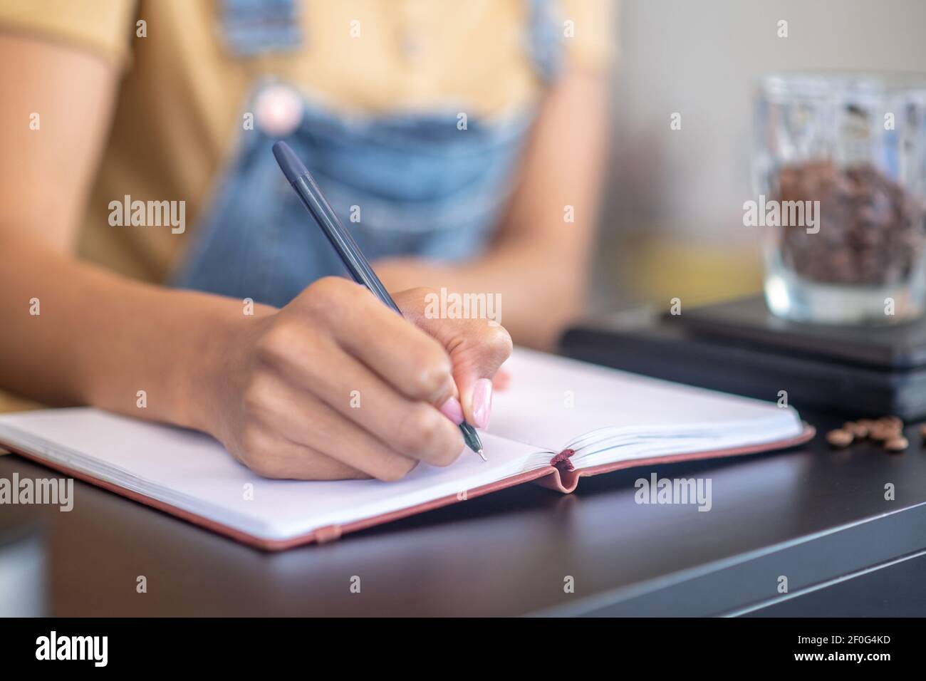 Scrittura a mano femminile con penna in taccuino sul bancone Foto Stock