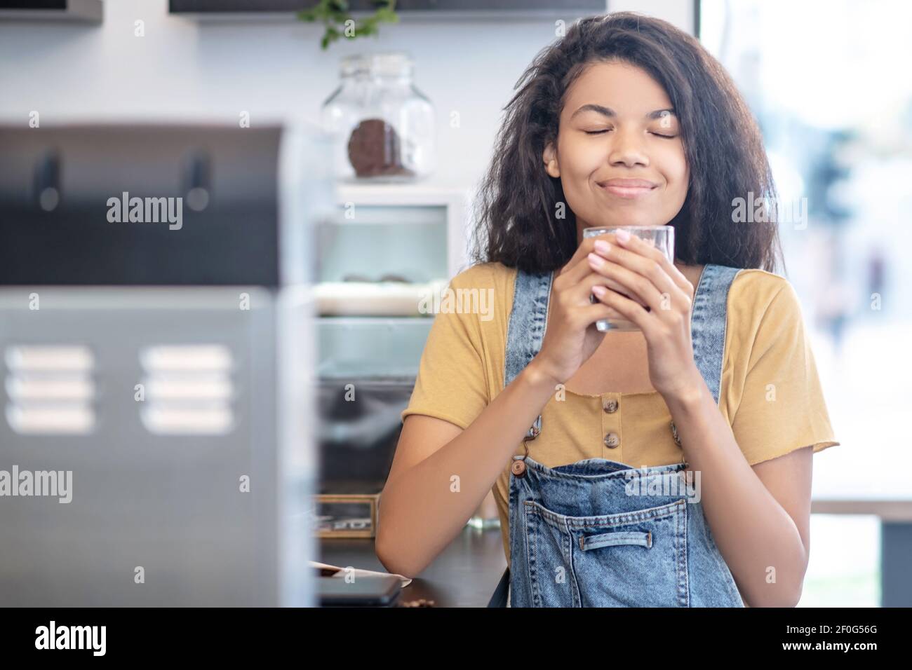 Donna contenta che inala l'aroma dei chicchi di caffè Foto Stock