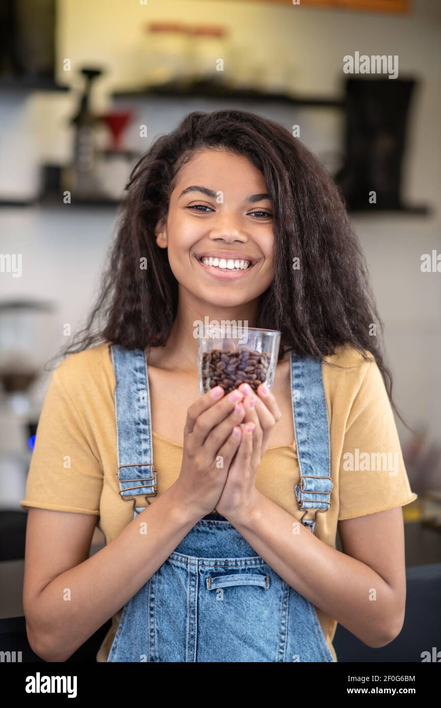 Donna splendente con un bicchiere di chicchi di caffè Foto Stock