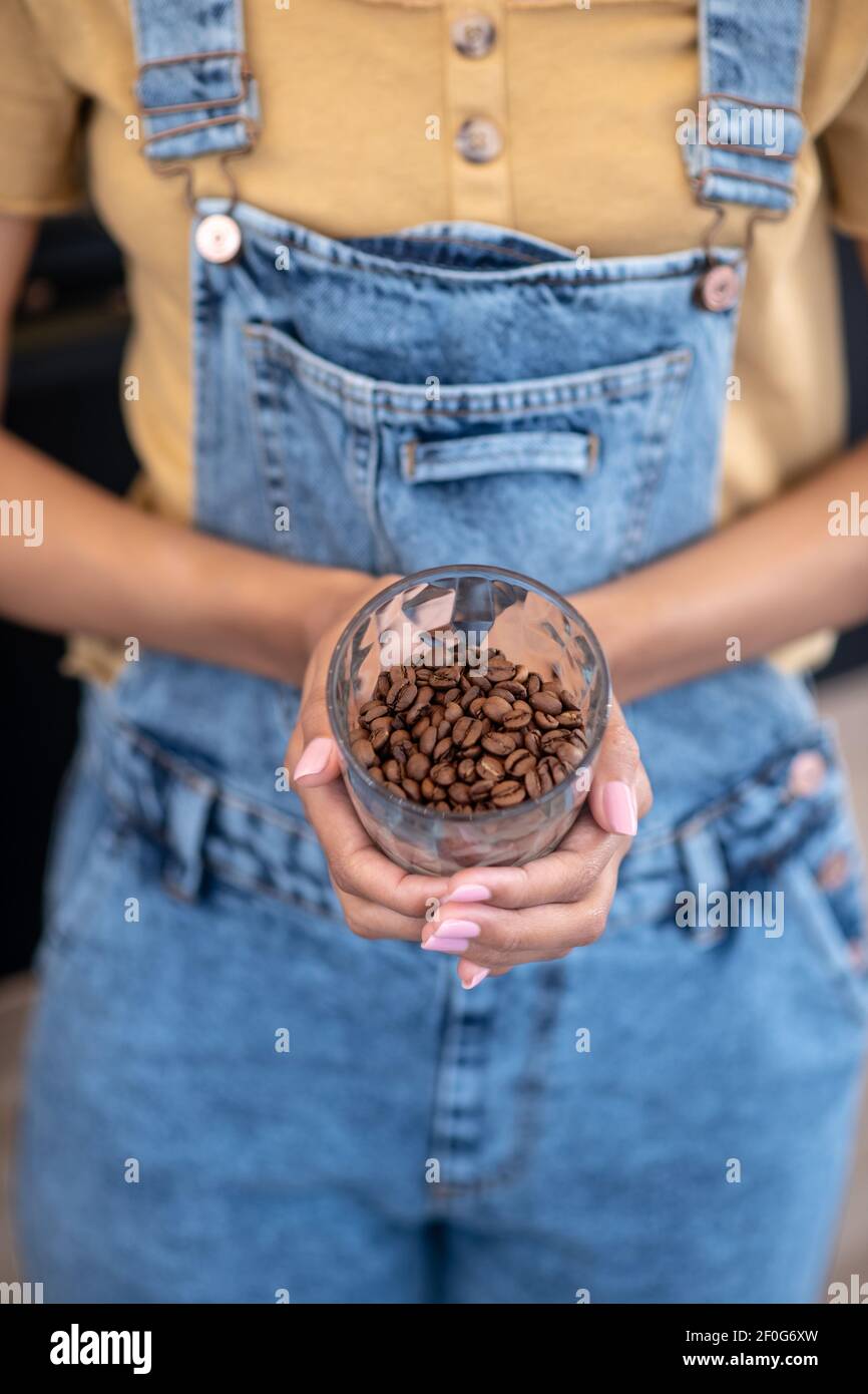 Bicchiere di chicchi di caffè in mani femminili Foto Stock