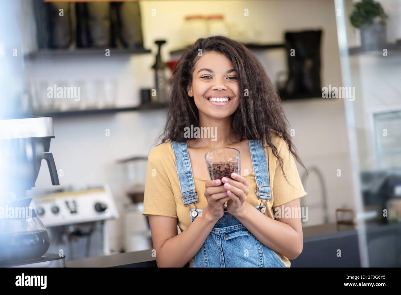 Donna felice con una porzione di chicchi di caffè in vetro Foto Stock