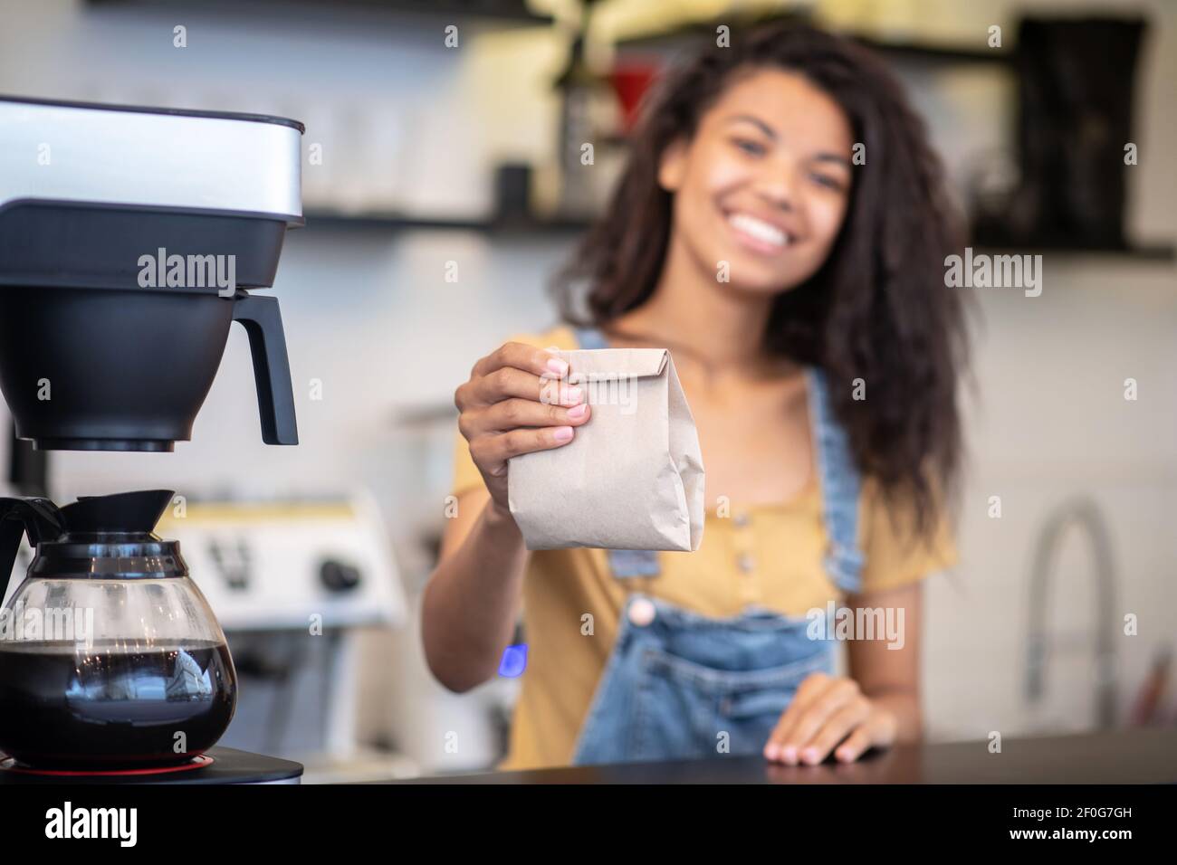 Piccolo sacchetto di carta in mano estensibile della barista femminile Foto Stock