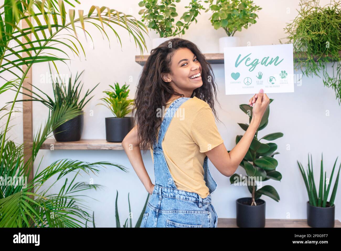 Donna in piedi indietro mostrando un cartello girando la testa Foto Stock