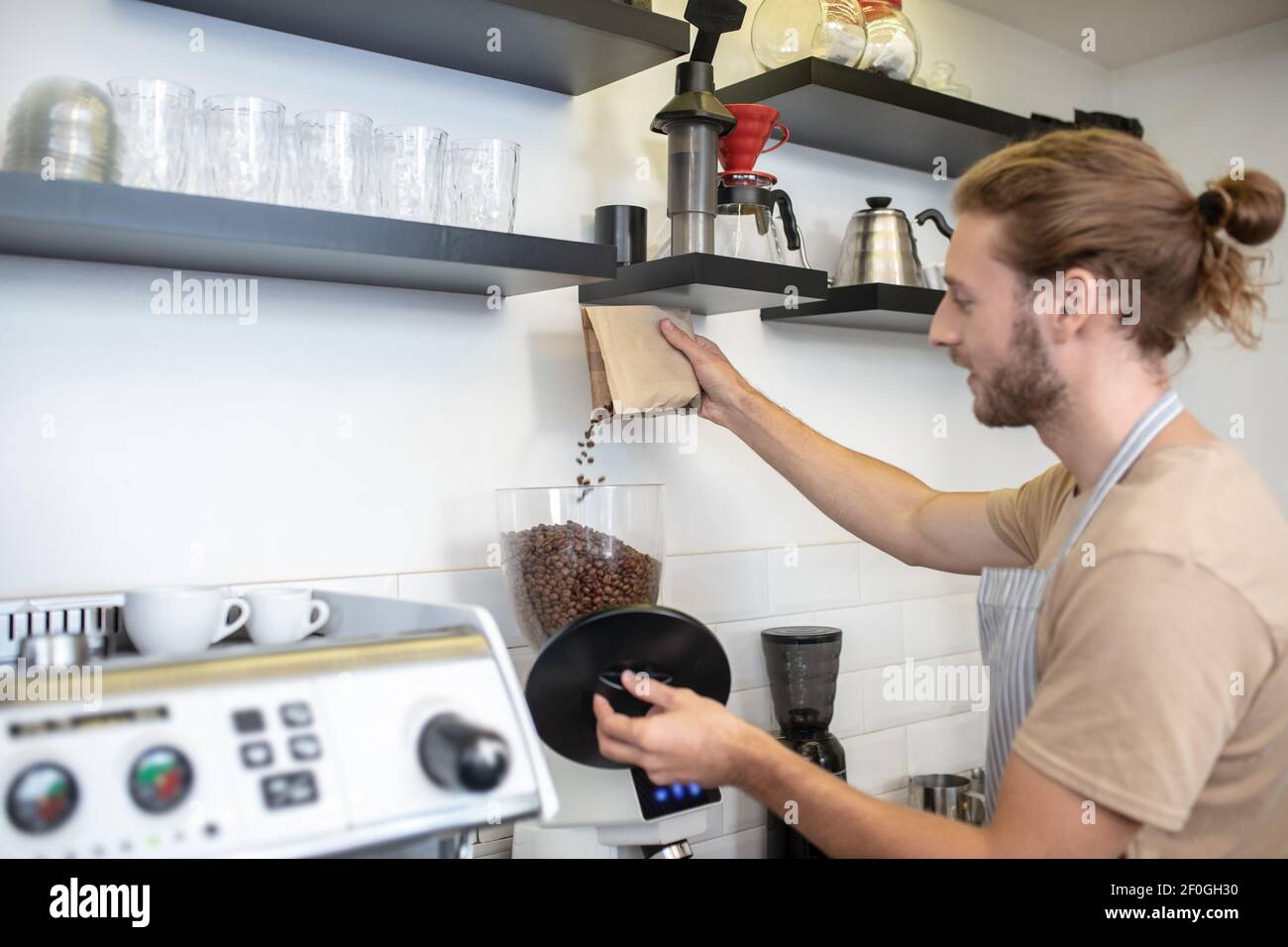 Uomo che versa i chicchi di caffè nel macinacaffè Foto Stock