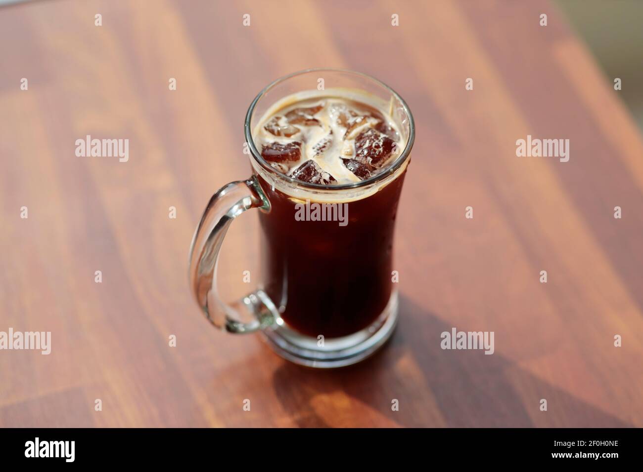 Un bicchiere di bevanda fredda in una tazza trasparente un tavolo di legno Foto Stock