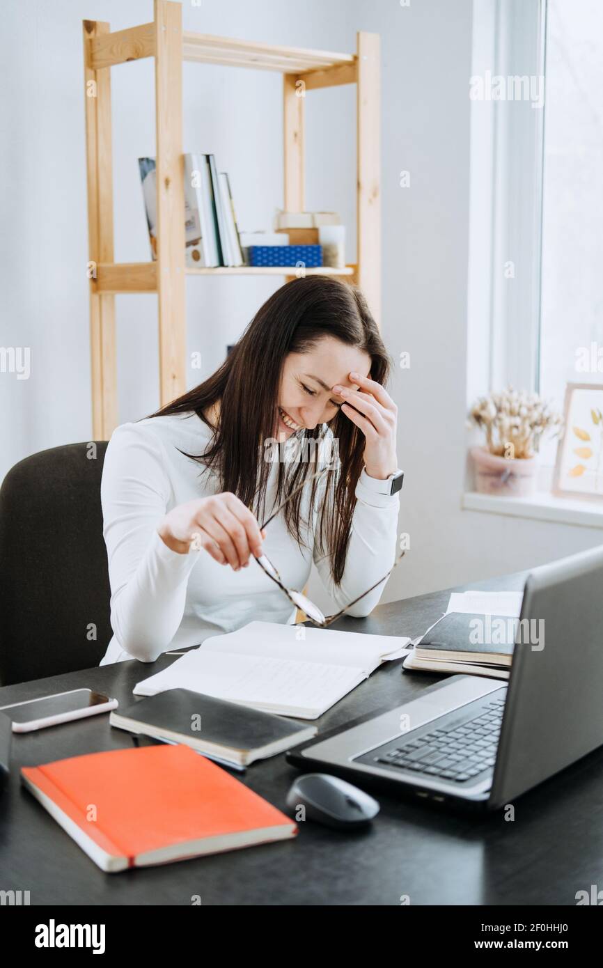 Processi finanziari di contabilità remota. Soluzione di contabilità online. Ritratto sincero di una ragioniere femminile che lavora con computer portatile, calcolatrice e documenti a casa Foto Stock