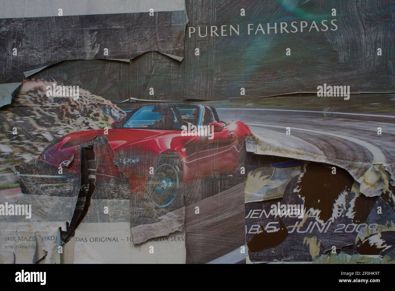Vecchio un poster danneggiato pubblicità di un Mazda Roadster Foto Stock