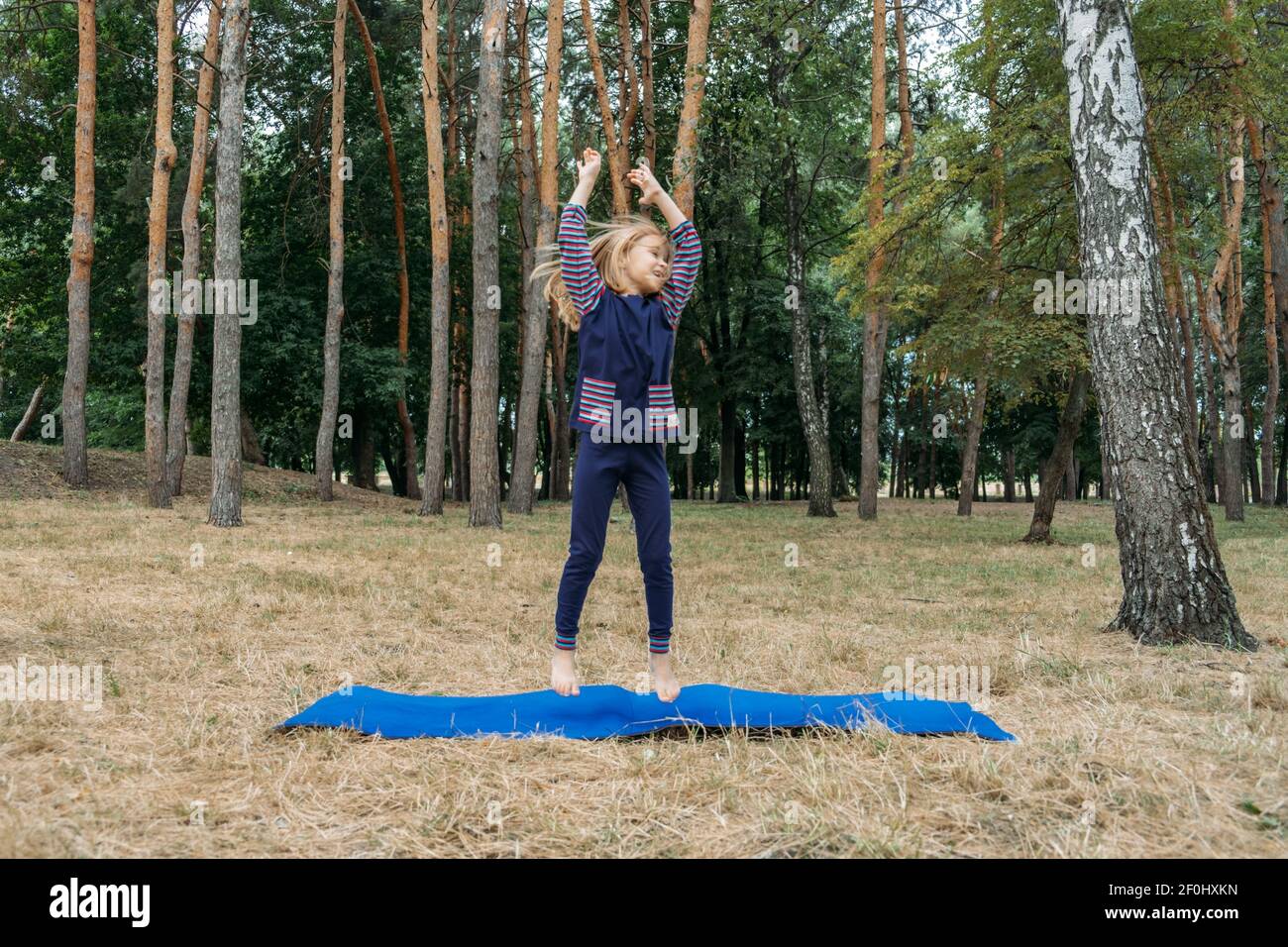 Circuito fitness all'aperto per bambini, giochi di attività estive. Attività all'aperto per bambini. Bambina che fa sport, esercizio fisico, allenamento all'aperto Foto Stock