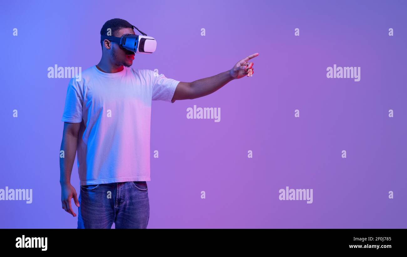 Young Black Man in VR cuffie toccare l'aria durante il gioco Videogioco Foto Stock