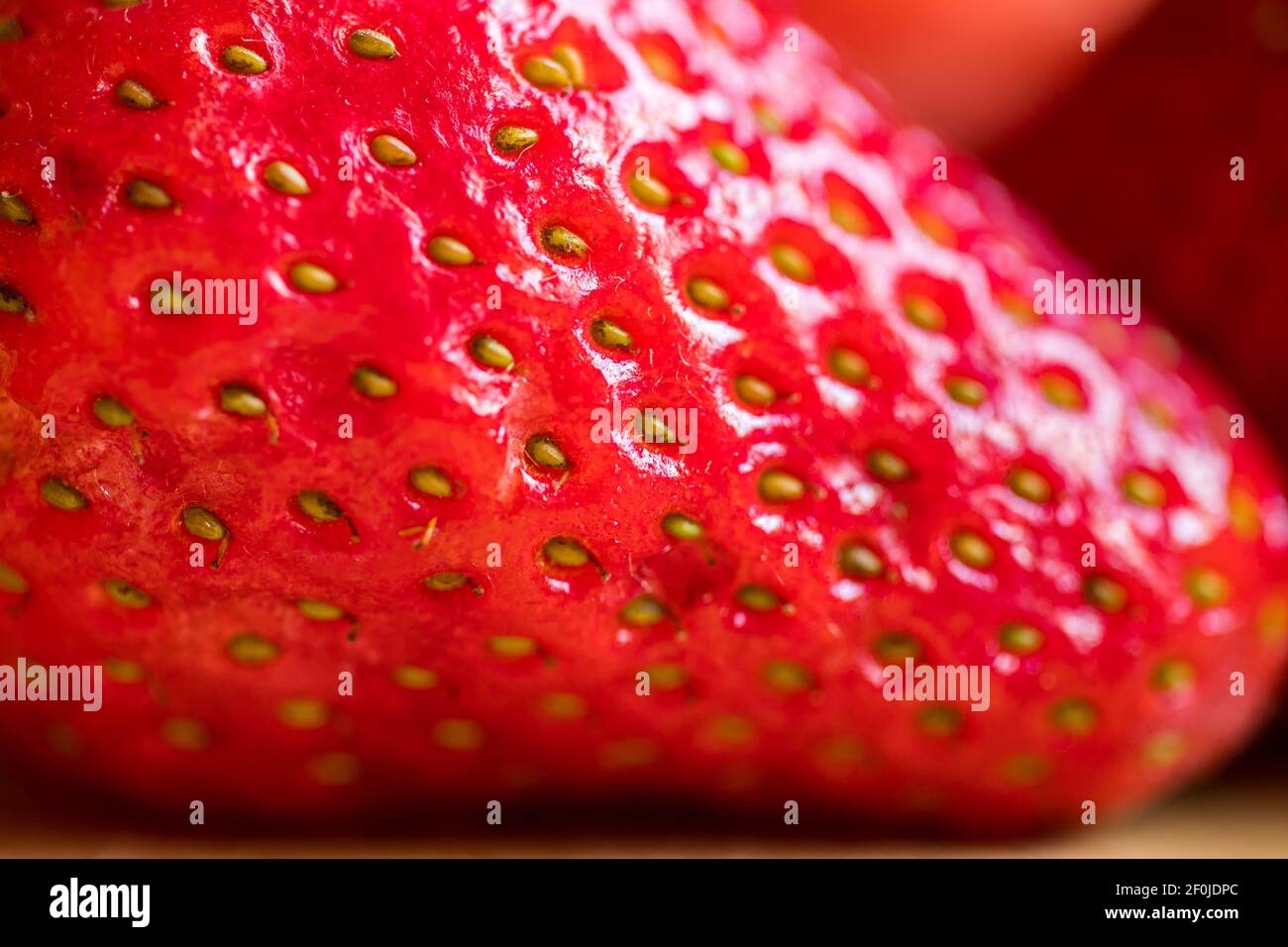 Primo piano di una fragola fresca matura. Frutti rossi luminosi con piccoli semi gialli Foto Stock