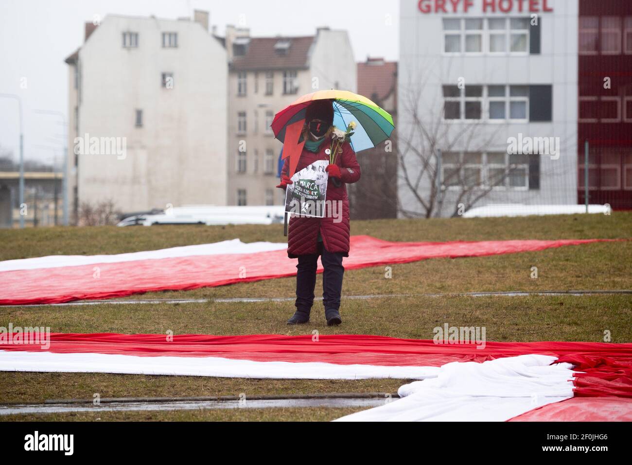 Donna con un simbolo di Strike femminile in Polonia - fulmine e ombrello arcobaleno visto vicino alla bandiera polacca a terra durante Manifa a Danzica.lo slogan di Manifa di quest'anno evidenzia il messaggio dello Strike femminile in Polonia - il mio corpo, la mia vita, La mia decisione - che è in corso da 4 mesi. I cittadini vogliono libertà e rispetto per i loro diritti e dignità. Manifa è una manifestazione femminista annuale organizzata in occasione della Giornata della Donna in varie parti della Polonia. Foto Stock