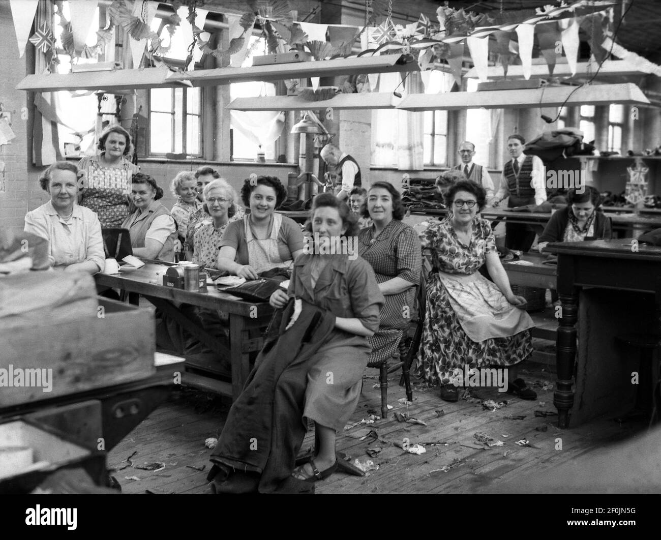 1953, storico, wiorker femminile presso la società di drappeggi, Hepworths di Leeds, Inghilterra, Regno Unito, seduto al lavoro panchine con macchine per la semina. Il pavimento della fabbrica è decorato con conigli e bandiere che celebrano l'incoronazione della Regina Elisabetta II al trono britannico che ha avuto luogo il 2 giugno 1953 all'Abbazia di Westminster. Le opere di Providence su Clay Pit Lane fu la fabbrica di Joseph Hepworth e Son, una compagnia di abbigliamento iniziata nel 1865 e che nel 1905 aveva 143 negozi. Più tardi nel secolo, Hepworths divenne Next. Foto Stock