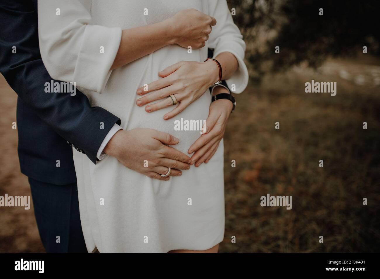 Bilder des Bauches einer schwangeren Frau. Ihre Hände und die Ihres Mannes liegen gefaltet auf ihrem runden Bauch. Foto Stock
