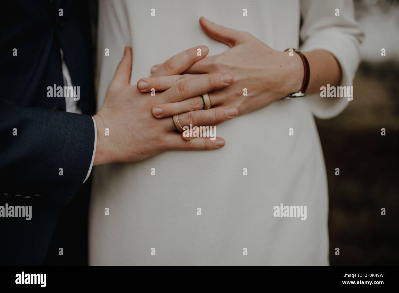 Bilder des Bauches einer schwangeren Frau. Ihre Hände und die Ihres Mannes liegen gefaltet auf ihrem runden Bauch. Foto Stock