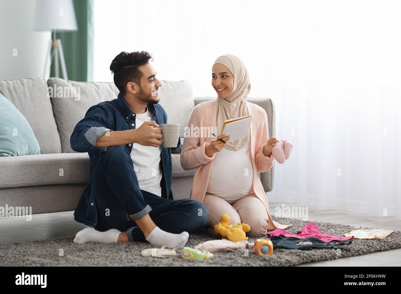 Felice coppia musulmana incinta ottenere geady per il parto, facendo checklist a casa Foto Stock